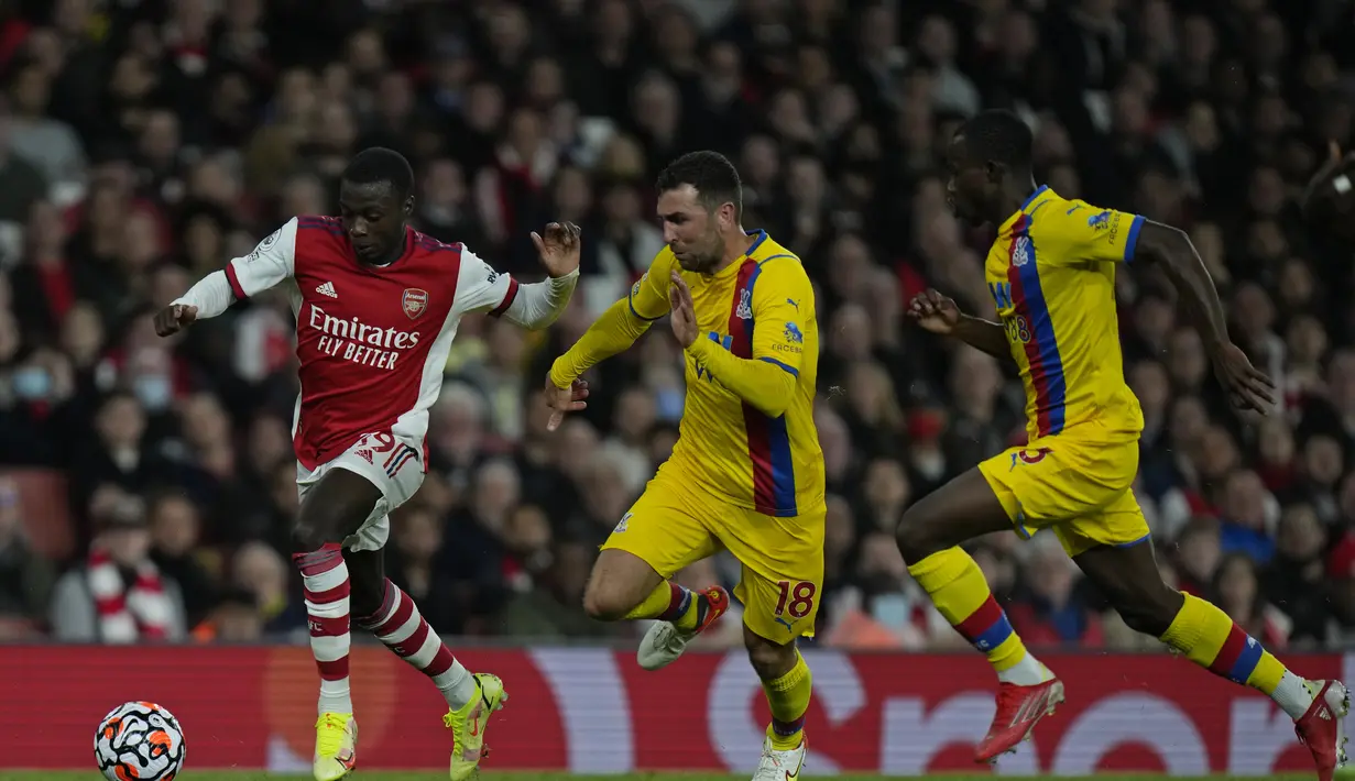 Penyerang Arsenal, Nicola pepe (kiri) membawa bola dari kejaran pemain Crystal Palace, James McArthur pada pertandingan lanjutan Liga Inggris di Stadion Emirates, London, Selasa (19/10/2021). Arsenal bermain imbang atas Crystal Palace 2-2. (AP Photo/Alastair Grant)
