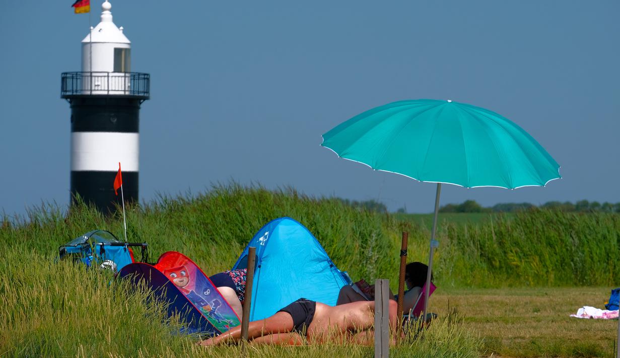 Warga berjemur saat suhu mencapai 34 derajat Celcius di dekat pantai Laut Utara di Wremen, Jerman barat (24/7/2019). Peramal cuaca memprediksi suhu tertinggi di seluruh Eropa barat yang terkena gelombang panas akan mencetak rekor suhu terbaru.  (AFP Photo/Patrik Stollarz)