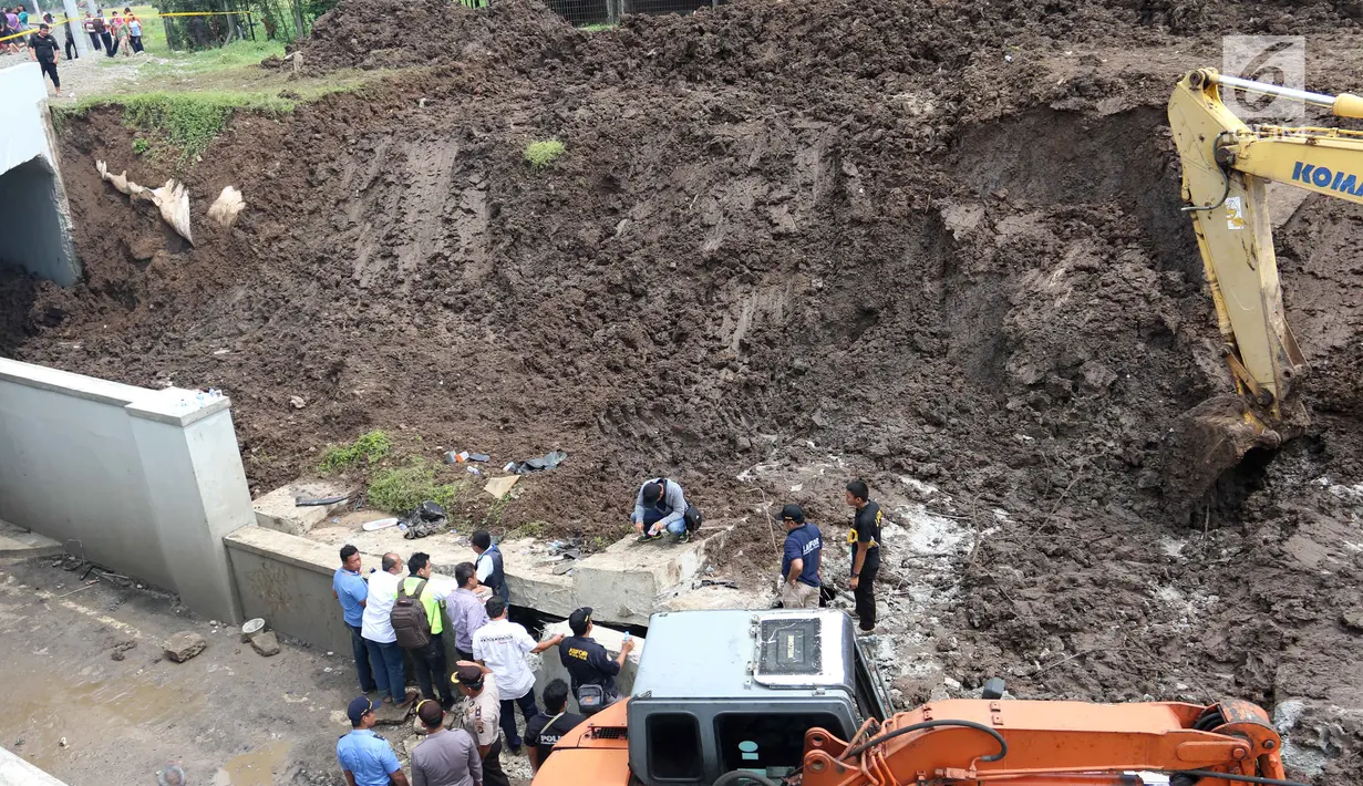 Petugas memeriksa kondisi mobil yang tertimbun longsor di Underpass Perimeter, Bandara Soetta, Tangerang, Banten, Selasa (6/2). Selain membersihkan longsor, alat berat juga dikerahkan untuk mengevakuasi mobil yang tertimbun. (Liputan6.com/Angga Yuniar)