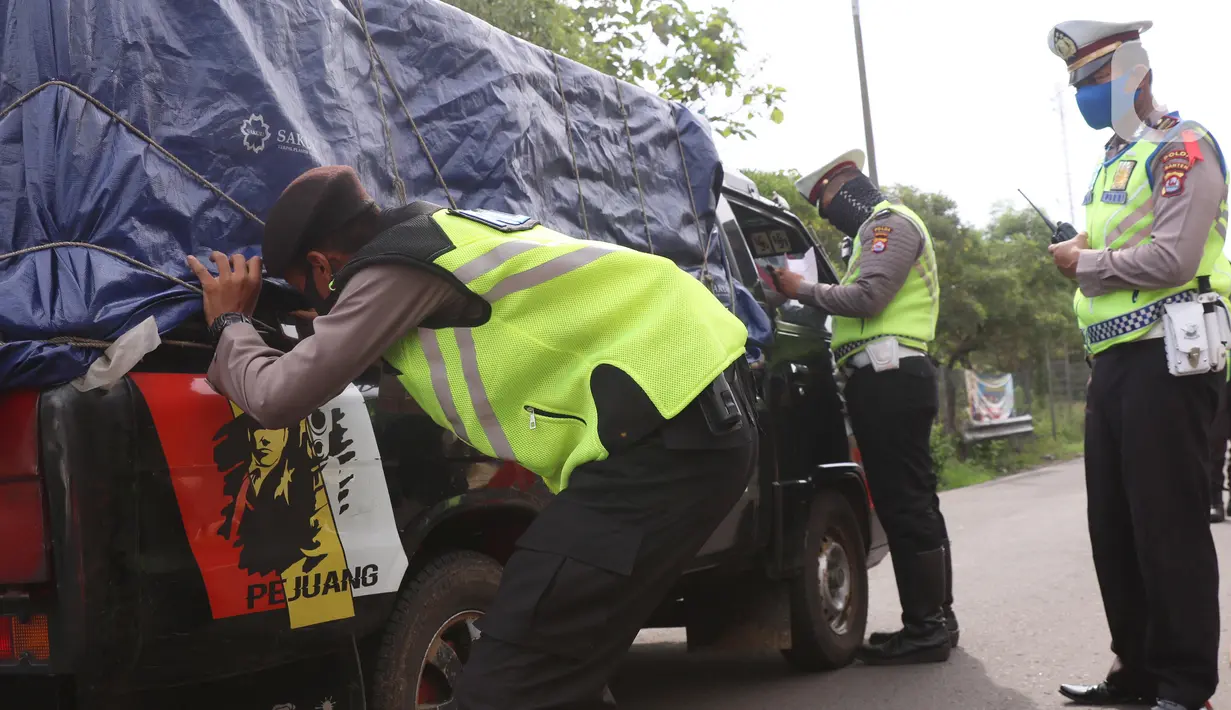 Petugas kepolisian melakukan pengecekan terhadap kendaraan yang keluar Tol Merak, Banten, Senin (18/5/2020). Pemeriksaan (check point) tersebut terkait larangan mudik guna penyekatan atau memeriksa kemungkinan pemudik yang akan keluar dari wilayah Jabodetabek. (Liputan6.com/Angga Yuniar)