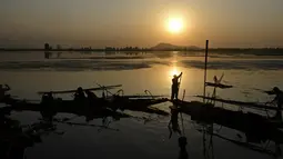 Aktivitas nelayan Kashmir saat matahari terbenam di danau Dal di Srinagar, India (12/9). Danau Dal yang luas dan bening. Diatasnya terhampar gerombolan daun bunga lotus. (AFP Photo/Tauseef Mustafa)