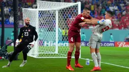 Pemain Serbia Nikola Milenkovic (tengah) mendorong pemain Swiss Granit Xhaka pada pertandingan sepak bola Grup G Piala Dunia 2022 di Doha, Qatar, 2 Desember 2022. Swiss melaju ke babak 16 besar Piala Dunia 2022 setelah mengalahkan Serbia dengan skor 3-2. (AP Photo/Ricardo Mazalan)