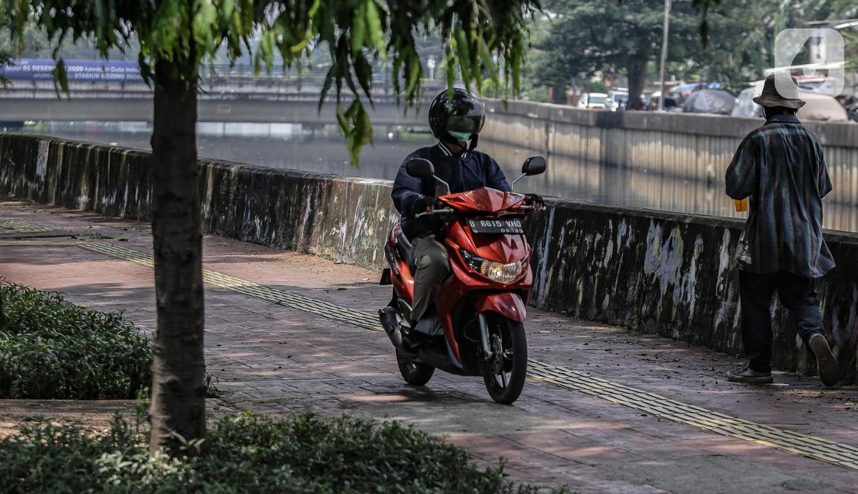 Pengendara motor melintas di atas trotoar pejalan kaki di kawasaan Daan Mogot, Jakarta, Senin (26/4/2021). Padatnya volume kendaraan pada jam kerja di kawasan tersebut membuat sejumlah pengendara motor nekat menggunakan trotoar yang merupakan
hak bagi pejalan kaki. (Liputan6.com/Faizal Fanani)