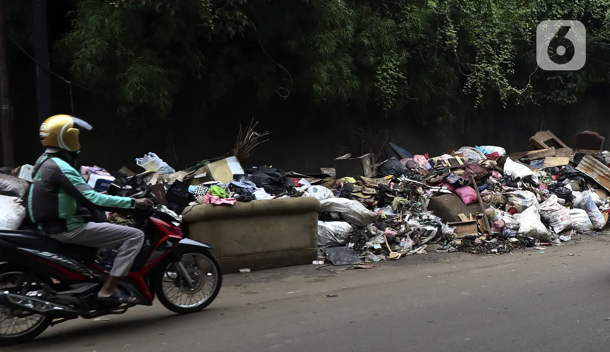 Pengendara melintas disamping tumpukan sampah di sepanjang jalan pascabanjir  di Kembangan, Jakarta Barat, Minggu (5/1/2020). Nantinya sampah-sampah ini akan diangkut oleh petugas kebersihan menggunakan truk pengangkut sampah yang akan dibawa ke TPA Bantar Gebang.  (Liputan6.com/Johan Tallo)