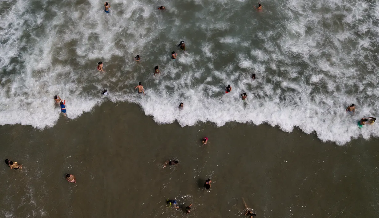 Orang-orang berenang di lepas pantai Los Angeles setelah baru-baru ini dibuka kembali di La Guaira, Venezuela, Jumat (23/10/2020). Pemberlakuan lockdown yang ketat akibat COVID-19 memaksa penutupan pantai di seluruh negeri pada Maret lalu dan dibuka kembali minggu ini. (AP/Matias Delacroix)