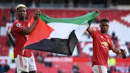 Penggawa MU, Paul Pogba dan Amad Diallo mengibarkan bendera Palestina usai ditahan imbang Fulham pada lanjutan Liga Inggris di Stadion Old Trafford, Rabu (19/5/2021) dinihari. Pogba dan Diallo menunjukkan solidaritas bagi Palestina yang tengah berseteru dengan Israel. (Laurence Griffiths/POOL/AFP)