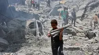 Seorang anak laki-laki membawa barang yang berhasil diselamatkan dari puing bangunan hancur akibat pengeboman Israel di kamp pengungsi Al-Shati di Kota Gaza pada 22 Juni 2024. ( AFP)