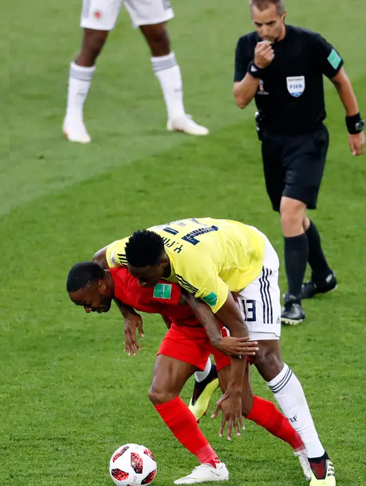 Wasit mengamati perebutan bola antara pemain timnas Inggris, Raheem Sterling dan bek Kolombia, Yerry Mina pada babak 16 besar Piala Dunia 2018 di Stadion Spartak, Selasa (3/7). Sebuah kejadian menarik tertangkap kamera pada laga itu. (AP/Antonio Calanni)