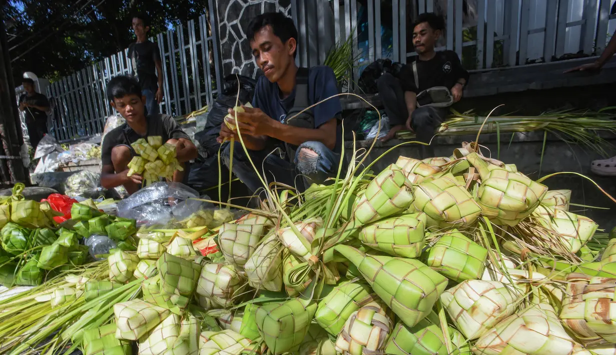Pedagang melayani pembuatan kulit ketupat di Pasar Pondok Labu, Jakarta Selatan, Minggu (30/3/2025). (merdeka.com/Arie Basuki)