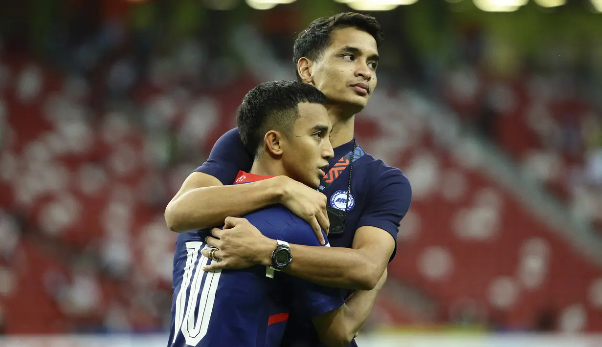 Pemain Singapura, Faris Ramli (kiri), sosok yang gagal mengeksekusi penalti ke gawang Indonesia dipeluk rekannya, salah satu penerima kartu merah, Safuwan Baharudin usai dikalahkan Indonesia. (AP/Suhaimi Abdullah)
