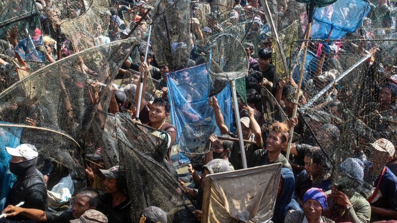 Tradisi menangkap ikan yang digelar di waduk ini menarik perhatian ratusan warga yang berbondong-bondong datang untuk berpartisipasi dalam kegiatan unik ini. Foto: DEVI RAHMAN / AFP<br>