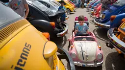 Seorang anak menaiki mobil-mobilan yang menyerupai Volkswagen Beetle dalam ajang pertemuan tahunan "Beetle club" di Yakum, Israel tengah (21/4). Di Indonesia mobil ini dikenal dengan VW Kodok. (AP Photo / Oded Balilty)