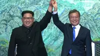 Pemimpin Korea Utara Kim Jong Un (kiri), dan Presiden Korea Selatan Moon Jae In berpegangan tangan dalam Konferensi Tingkat Tinggi (KTT) Antar-Korea di Panmunjom. (AFP/Arsip)
