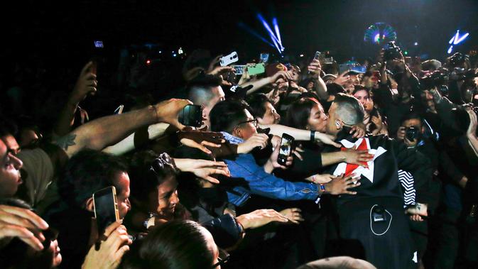 Penyanyi asal Inggris Robbie Williams mencium seorang fans saat tampil selama Festival Musik Corona Capital di Meksiko (17/11). (AP Photo/Eduardo Verdugo)