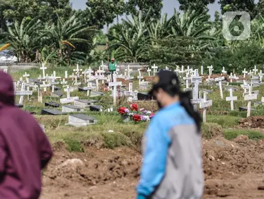 Warga melintas di kompleks pemakaman khusus Covid-19 di TPU Rorotan, Jakarta, Rabu (2/3/2022). Lurah Rorotan Idham Mugabe mengungkapkan sejak digunakan pada Maret 2021, saat ini luas lahan TPU Rorotan mencapai 25 hektare dan telah terisi sebanyak 6.388 petak makam. (merdeka.com/Iqbal S Nugroho)