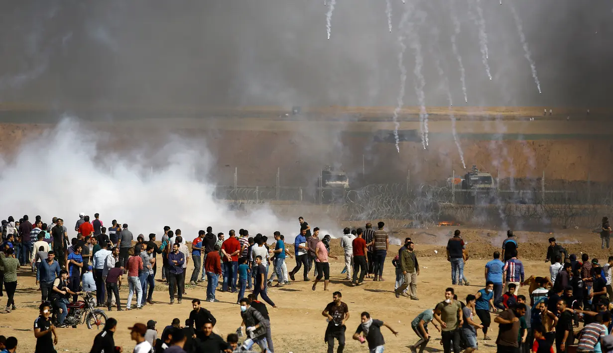 Sekelompok demonstran Palestina berlarian saat ditembakkan gas air mata oleh paskuan Israel di jalur Gaza (11/5). Warga Palestina ini menuntut dikembalikannya hak dan tanah tempat tinggal mereka yang diduduki oleh Israel. (AFP Photo/Mohammed Abed)