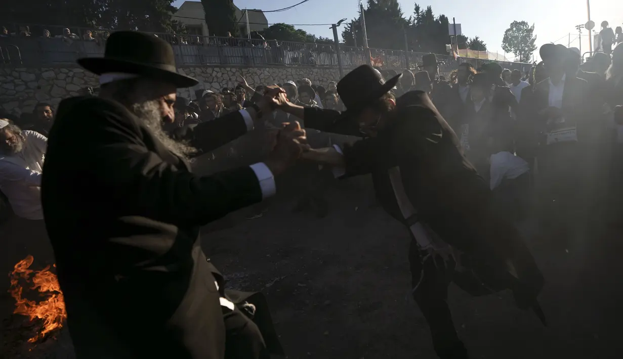 Orang-orang Yahudi Ultra Ortodoks menari di sekitar api unggun saat perayaan Lag BaOmer di situs makam tradisional Rabbi Shimon Bar Yochai di Gunung Meron, Israel, Kamis (19/5/2022). Orang Israel menyalakan api unggun selama perayaan Lag BaOmer untuk memperingati berakhirnya wabah yang dikatakan telah memusnahkan orang Yahudi di zaman Romawi. (AP Photo/Ariel Schalit)