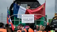 Seorang pria memegang bendera Perancis dan Cina di atas kereta barang di stasiun Saint-Priest, Lyon, Prancis, (21/4). Untuk pertama kali, kereta barang yang mengangkut 41 kontainer dari China tiba di Prancis. (AFP PHOTO/JEFF PACHOUD)