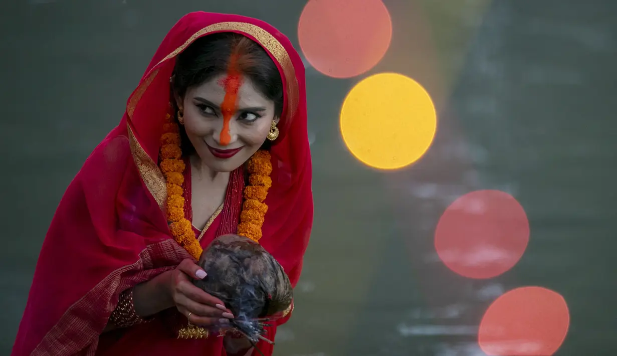 Seorang wanita Nepal berdoa kepada matahari terbenam selama festival Chhath Puja di tepi Sungai Bagmati di Kathmandu, Nepal, Rabu (10/11/2021). Ritual dilakukan untuk berterima kasih kepada Dewa Matahari karena telah menopang kehidupan di bumi. (AP Photo/Niranjan Shrestha)
