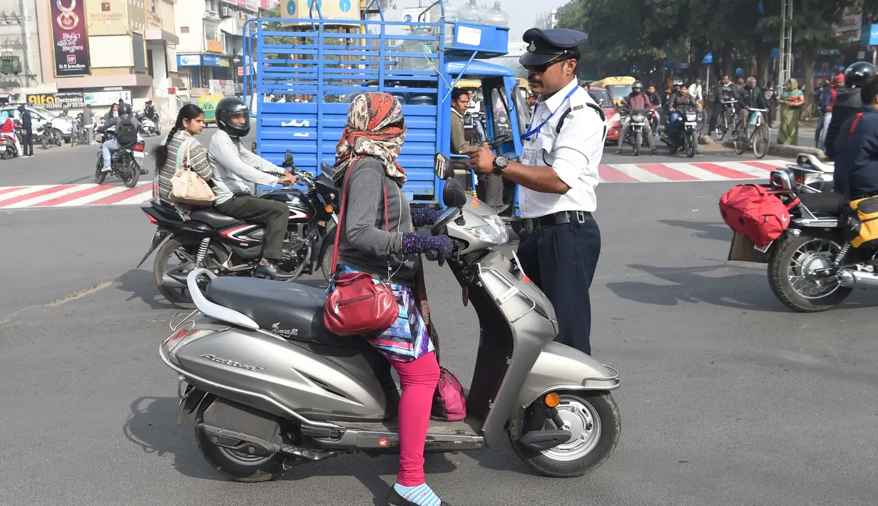 Polisi lalu lintas India Ranjeet Singh memperingatkanpengendara motor di persimpangan Indore, India (22/12). (AFP Photo/Indranil Mukherjee)