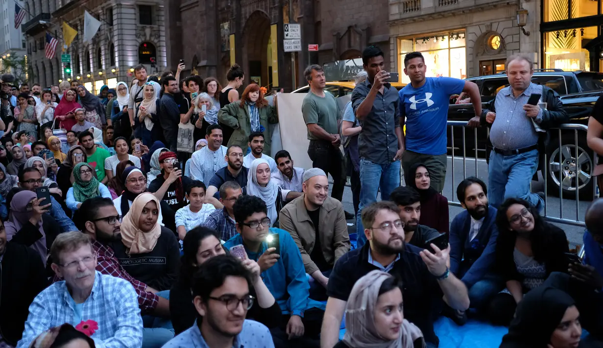 Umat muslim dan aktivis pendukung menunggu waktu berbuka puasa di dekat Trump Tower, New York, Kamis (1/6). Ratusan muslim berdemo memprotes retorika dan kebijakan Donald Trump yang xenophobia, seperti larangan perayaan Ramadan di AS. (Jewel SAMAD/AFP)