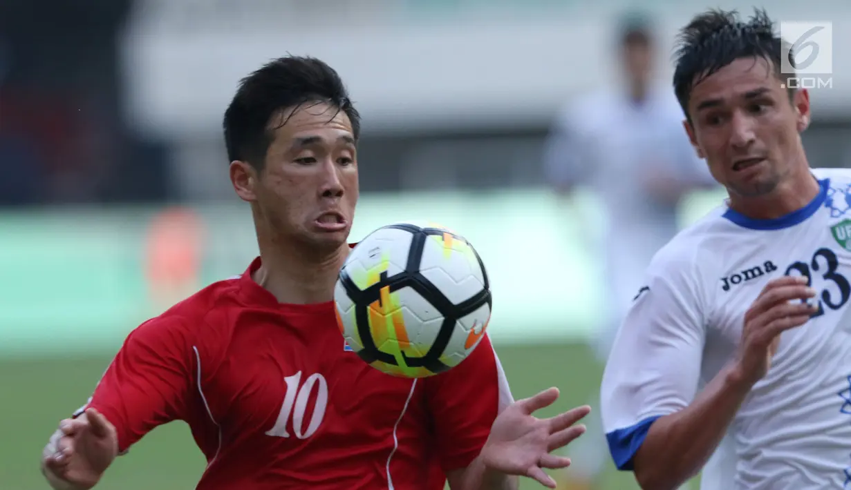 Pemain Korea Utara, Jo Sol Song (kiri) berebut bola dengan pemain Uzbekistan, Alijanov Likhomjon pada laga perdana PSSI Anniversary 2018 di Stadion Pakansari, Kab Bogor, Jumat (27/4). Laga berakhir imbang 2-2. (Liputan6.com/Helmi Fithriansyah)