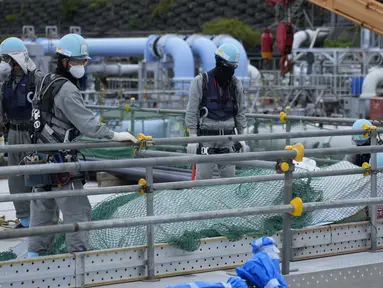 Para pekerja menyingkirkan bahan bangunan sebelum istirahat makan siang di pembangkit listrik tenaga nuklir Fukushima Daiichi, di kota Futaba, timur laut Jepang, Jumat, 14 Juli 2023. (AP Photo/Hiro Komae)