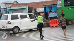 Petugas kepolisian membantu warga menyeberang jalan di Perempatan Cileunyi, Jawa Barat, Jumat (1/7). Mulai banyaknya kendaraan pemudik membuat petugas kepolisian membantu pejalan kaki yang ingin menyeberang. (Liputan6.com/Immanuel Antonius) 