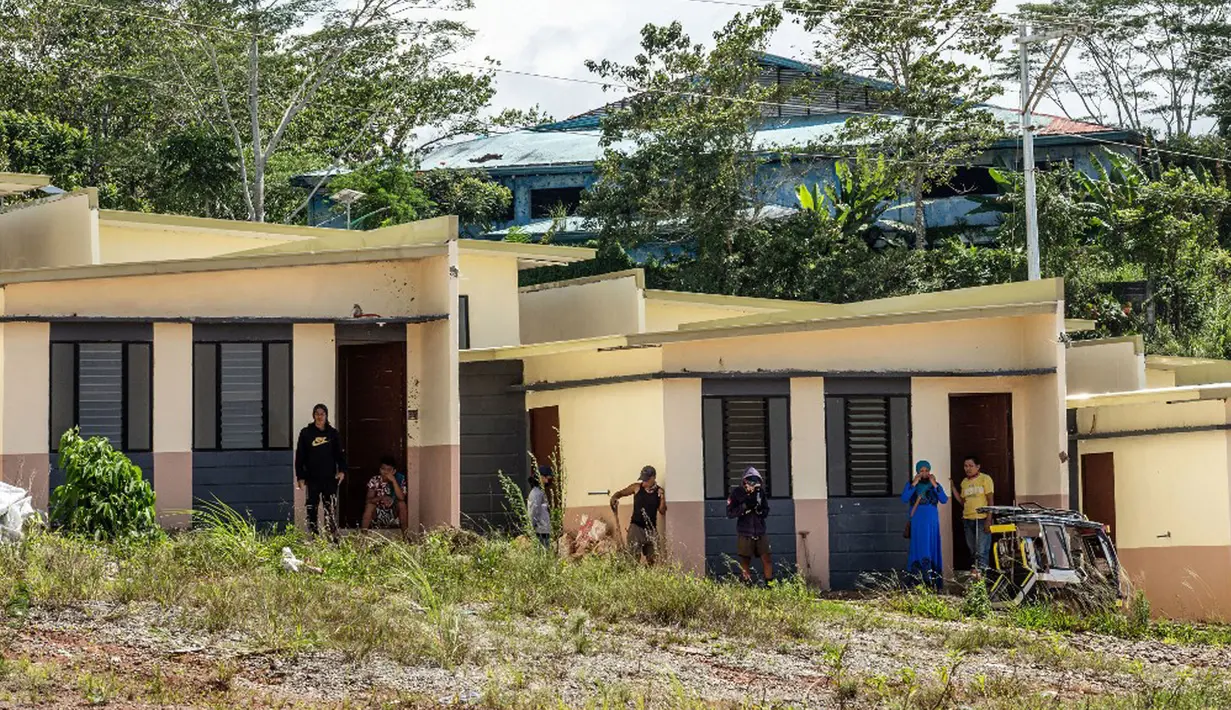 Penduduk berdiri di luar rumah yang baru dibangun empat tahun setelah militan ISIS mengepung Kota Marawi di Mindanao, Filipina, 23 Mei 2021. Lebih dari 1.000 nyawa terenggut dalam pertempuran lima bulan antara pasukan pemerintah dengan militan ISIS. (Ferdinandh CABRERA/AFP)