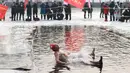 Seorang penggemar renang musim dingin melompat ke danau yang sebagian beku di Shenyang, di provinsi Liaoning, China pada 25 Januari 2022. Berenang di musim dingin adalah kegiatan olahraga yang jarang dijumpai kecuali di beberapa negara dengan musim dingin yang cukup panjang. (STR/AFP)