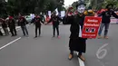 Seorang demonstran mengenakan topeng berjalan membawa poster saat aksi 100 Hari Pemerintahan Joko Widodo-Jusuf Kalla di depan Istana Negara, Jakarta, Rabu (28/1/2015). (Liputan6.com/Miftahul Hayat)