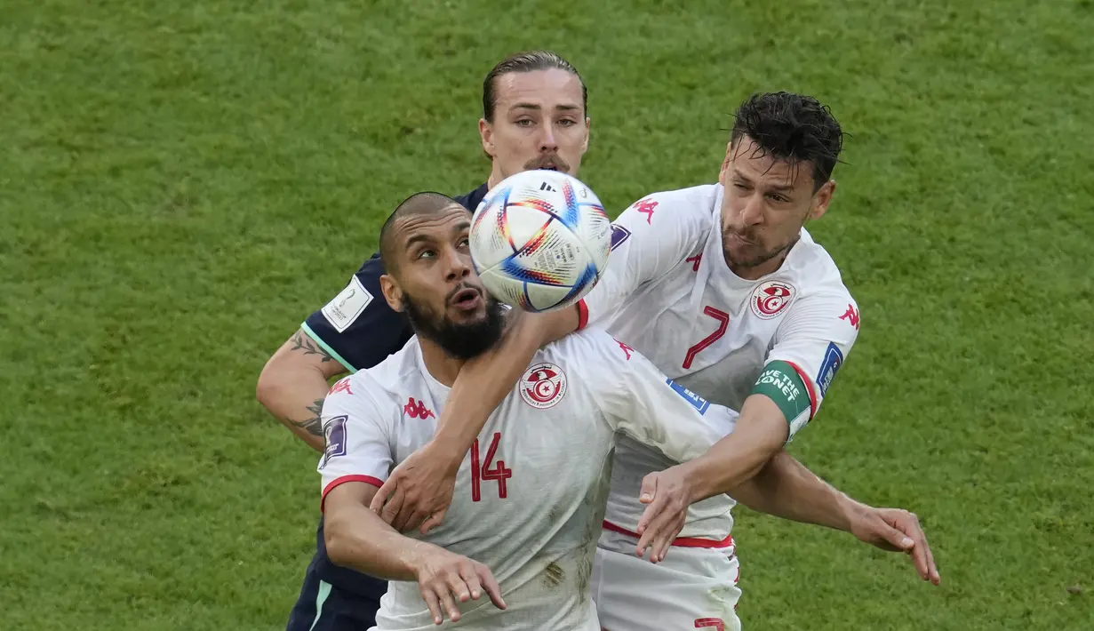 Pemain Tunisia, Aissa Laidouni dan Youssef Msakni berebut bola dengan pemain Australia, Jackson Irvine  selama pertandingan grup D Piala Dunia 2022 di Stadion Al Janoub di Al Wakrah, Qatar, Sabtu, 26 November 2022.  Kemenangan ini membuat Australia untuk sementara berada di posisi dua klasemen Grup D Piala Dunia 2022 dengan torehan tiga poin, di bawah Prancis yang unggul head to head. (AP Photo/Natacha Pisarenko)
