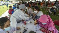 Dokter memeriksa kondisi warga di klinik vaksinasi massal darurat di lapangan sepak bola di Surabaya, Jawa Timur, Selasa (6/7/2021). Indonesia tengah memerangi gelombang infeksi baru yang belum pernah terjadi sebelumnya. (JUNI KRISWANTO/AFP)
