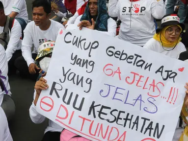 Peserta aksi mengangkat poster berisi pesan penolakan Rancangan Undang-Undang (RUU) Omnibus Law Kesehatan saat aksi di kawasan Patung Kuda Arjuna Wiwaha, Jakarta, Senin (8/5/2023). (Liputan6.com/Herman Zakharia)