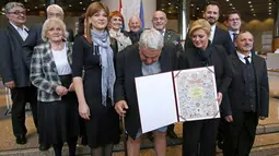 Kepala Komisi HAM Helsinki Kroasia, Ivan Zvonimir Cicak harus menahan malu ketika celananya melorot tepat saat sesi foto dengan Presiden Kroasia Kolinda Grabar-Kitrarovic di Zagreb, Selasa (8/12). (STRINGER / AFP)