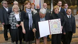 Kepala Komisi HAM Helsinki Kroasia, Ivan Zvonimir Cicak harus menahan malu ketika celananya melorot tepat saat sesi foto dengan Presiden Kroasia Kolinda Grabar-Kitrarovic di Zagreb, Selasa (8/12). (STRINGER / AFP)