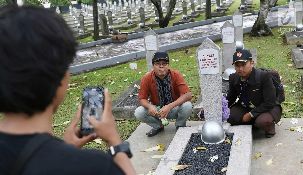 Warga saat foto di Taman Makam Pahlawan Kalibata di Jakarta, Kamis (9/11). Pembersihan tersebut dilakukan guna menyambut Hari Pahlawan yang diperingati setiap 10 November. (Liputan6.com/Immanuel Antonius)
