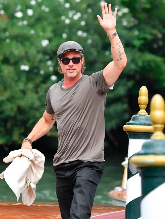 Aktor Brad Pitt melambaikan tangannya saat tiba di Pantai Lido untuk menghadiri Venice Film Festival 2019, Venesia, Italia, Rabu (28/8/2019). Selain Brad Pitt, bintang-bintang film besar lainnya juga telah tiba untuk menghadiri Venice Film Festival 2019. (Ettore Ferrari/ANSA via AP)