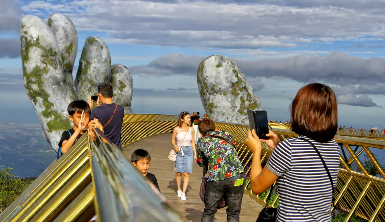 Pengunjung mengambil gambar saat berjalan di sepanjang Golden Bridge di Perbukitan Ba Na dekat Danang, Vietnam, Selasa (31/7). Golden Bridge dirancang untuk membuat pengunjung merasa seperti berjalan-jalan di atas tangan Tuhan. (Linh PHAM/AFP)