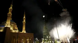 Kembang api dinyalakan di dekat pohon Natal yang dirancang oleh desainer Lebanon, Elie Saab di depan Masjid Al-Amin, di pusat kota Beirut, 12 Desember 2015. (REUTERS/Jamal Saidi)