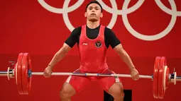 Lifter andalan Indonesia, Eko Yuli Irawan berusaha mengangkat beban saat bertanding dalam kelas 61kg putra Grup A cabor angkat besi Olimpiade Tokyo 2020 di Tokyo International Forum, Minggu (25/7/2021). Eko Yuli meraih medali perak dengan total angkatan 302 kg. (Vincenzo PINTO / AFP)