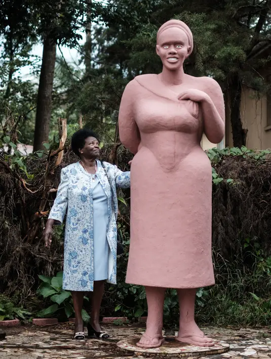 Istri pematung Edward Njenga, Hannah Njenga berdiri di samping karya sang suami yang diberi nama 'Mama Ngina' di rumah mereka di Nairobi, Kenya, Senin (12/3). (AFP PHOTO/Yasuyoshi CHIBA)