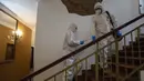 Petugas kesehatan dengan APD menaiki tangga untuk mengunjungi tunawisma pasien virus corona di sebuah hotel di Praha, Senin (8/3/2021). Hotel yang dulu menjadi tujuan wisatawan internasional itu kini membuka pintunya bagi para tunawisma yang terpapar Covid-19 atau perlu karantina. (MICHAL CIZEK/AFP)