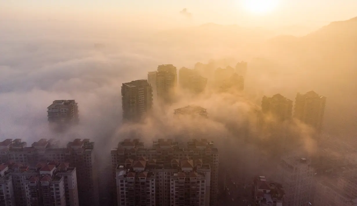 Foto udara ini menunjukkan bangunan yang diselimuti kabut pagi di Bijie, provinsi Guizhou barat daya China (18/11/2021).  Pada 10 November 2011, bekas Prefektur Bijie diubah menjadi kota setingkat prefektur, dan bekas kota tingkat kabupaten Bijie diubah namanya menjadi Distrik Qixingguan. (AFP/STR)