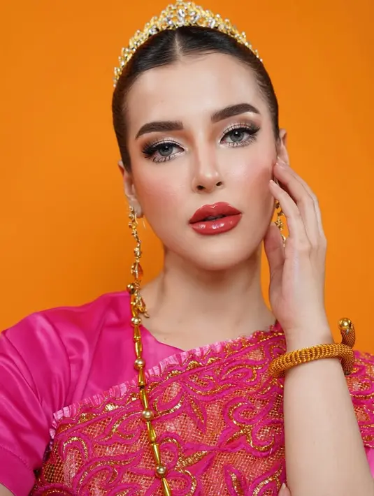Wajah Tasya dirias dengan gaya makeup Thai yang identik dengan kulit wajah flawless, efek glowing, dan detail mata yang tegas namun feminin. Alis diarsir tebal dan terdefinisi dengan sempurna, sementara riasan mata diperkaya dengan eyeliner tajam dan bulu mata lentik dramatis. [@tasyafarasya].