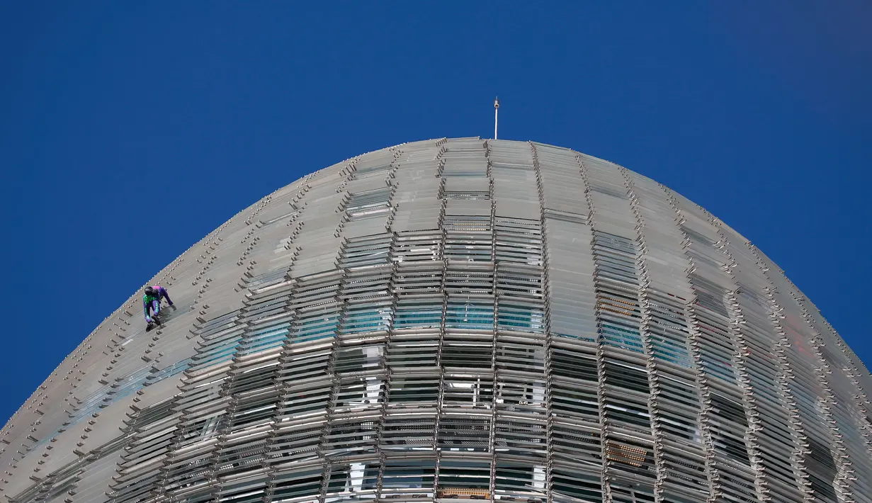 Pendaki pencakar langit, Alain Robert, yang juga dikenal sebagai 'Spiderman Prancis' memanjat Menara Agbar setinggi 144 meter di Barcelona, Rabu (4/3/2020). Aksi yang dilakukan tanpa menggunakan alat pengaman itu sebagai bentuk protes terhadap kepanikan atas epidemi virus corona. (AP/Joan Mateu)