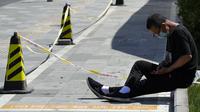 Seorang warga yang mengenakan masker duduk pada trotoar di Beijing, China, Selasa (3/5/2022). China telah berpegang teguh pada pendekatan ketat 'Nol COVID' yang membatasi perjalanan, menguji massal seluruh kota, dan mendirikan fasilitas sementara yang luas untuk mencoba mengisolasi setiap orang yang terinfeksi. (AP Photo/Ng Han Guan)