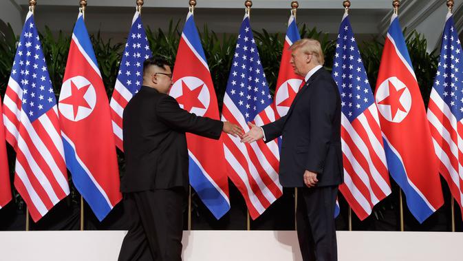 Presiden AS Donald Trump meraih jabat tangan pemimpin Korea Utara Kim Jong-un dalam pertemuan bersejarah di resor Capella, Pulau Sentosa, Singapura, Selasa (12/6). Pertemuan Trump dan Kim diawali dengan jabat tangan bersejarah. (AP/Evan Vucci)