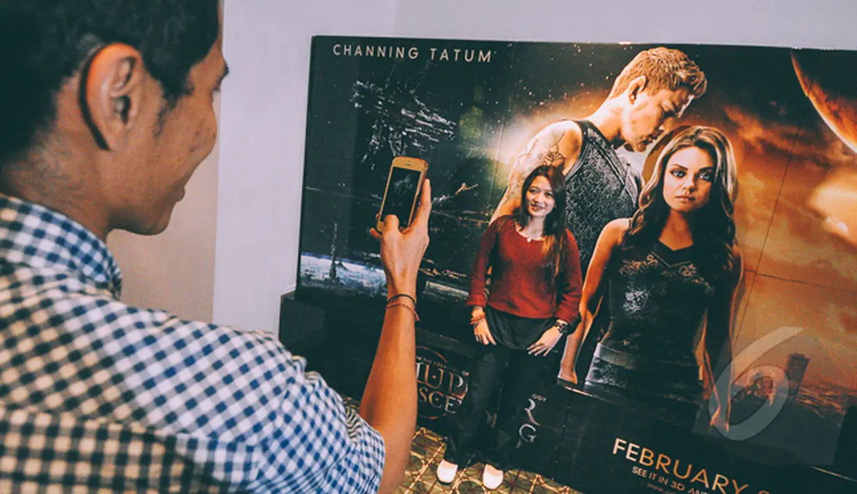 Seorang pengunjung berpose di dekat poster fIlm Jupiter Ascending saat Premier Film Jupiter Ascending di Plaza Indonesia XXI, Jakarta, Selasa (3/2/2015). (Liputan6.com/Faizal Fanani)