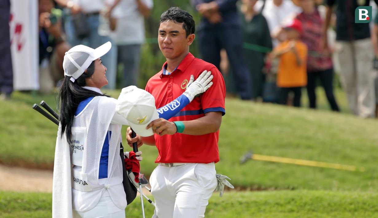Caddie Naraajie Emerald Ramadhan Putra menghibur Naraajie Emerald Ramadhan Putra yang akhirnya hanya berhasil menduduki peringkat keempat pada turnamen golf pro BRI Indonesia Open 2019, Minggu (1/9/2019).
(Bola.com/Peksi Cahyo)